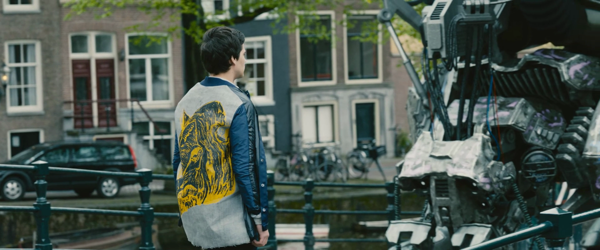 A person faces a robot on a city street